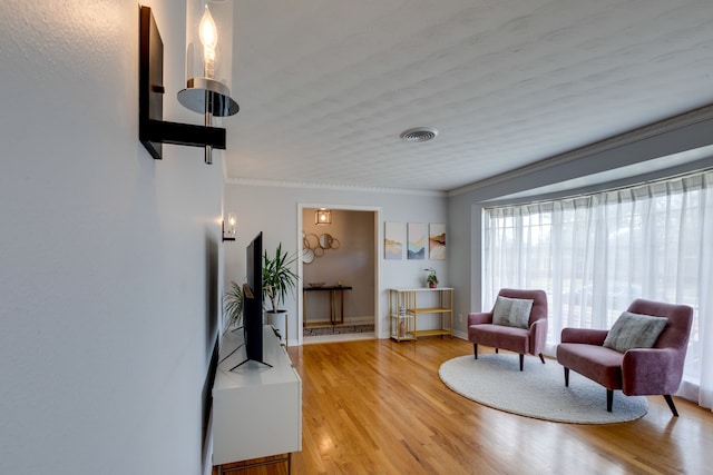 sitting room featuring wood-type flooring and ornamental molding