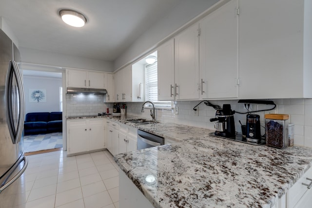 kitchen with light stone countertops, appliances with stainless steel finishes, decorative backsplash, sink, and white cabinets