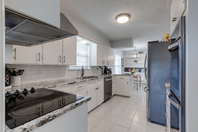 kitchen with appliances with stainless steel finishes, sink, white cabinets, extractor fan, and decorative backsplash