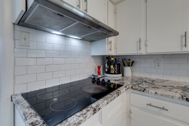 kitchen with white cabinets, extractor fan, black electric stovetop, and tasteful backsplash