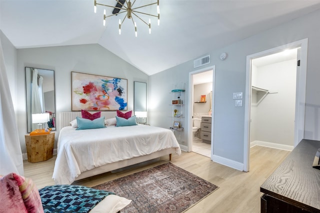 bedroom with connected bathroom, a notable chandelier, a closet, a walk in closet, and light hardwood / wood-style flooring