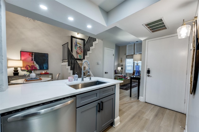 kitchen with dishwasher, gray cabinets, sink, light hardwood / wood-style flooring, and hanging light fixtures