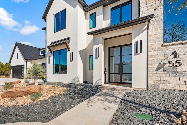 view of exterior entry featuring a garage and french doors