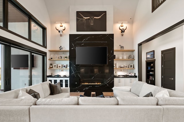 living room featuring a premium fireplace and high vaulted ceiling