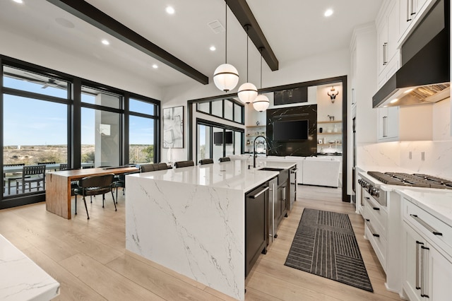 kitchen with stainless steel gas stovetop, white cabinets, decorative light fixtures, beam ceiling, and light stone counters