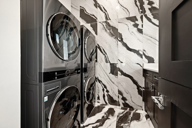 laundry area with cabinets and stacked washer / drying machine