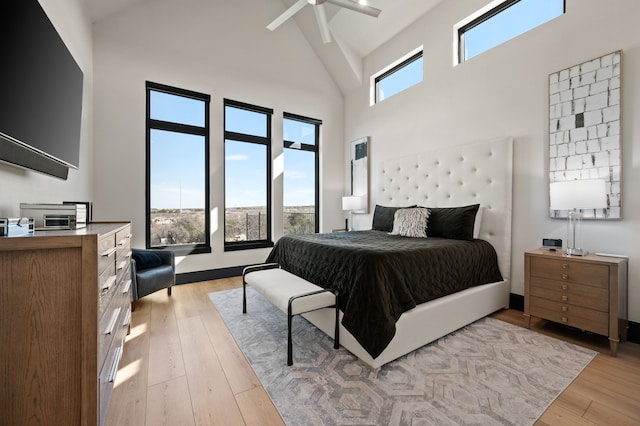 bedroom featuring light wood-type flooring, a high ceiling, and ceiling fan