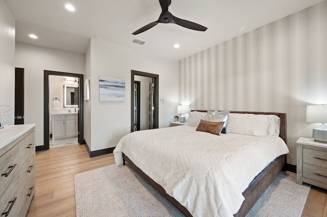 bedroom featuring ceiling fan, ensuite bathroom, and light hardwood / wood-style flooring