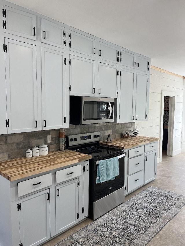 kitchen featuring decorative backsplash, butcher block counters, stainless steel appliances, and white cabinetry