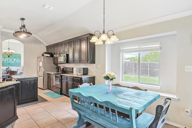 dining space featuring lofted ceiling, a notable chandelier, light tile patterned flooring, and ornamental molding