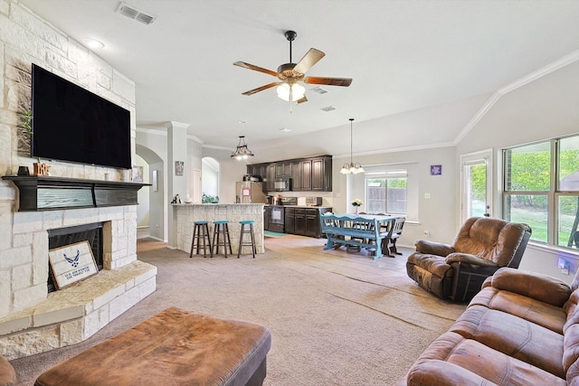 carpeted living room featuring ceiling fan, ornamental molding, lofted ceiling, and a stone fireplace