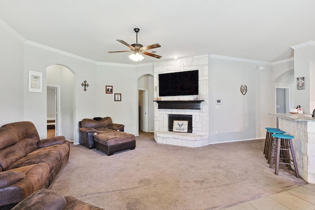 living room featuring carpet, ornamental molding, a fireplace, and ceiling fan