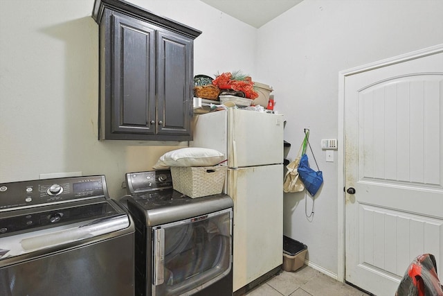 clothes washing area featuring washing machine and dryer, cabinets, and light tile patterned flooring