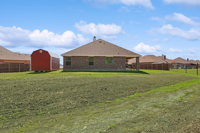 rear view of house featuring a yard and a storage shed