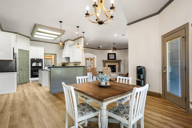 dining space with light wood-type flooring, ornamental molding, and a fireplace