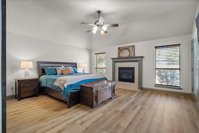 bedroom featuring lofted ceiling, light hardwood / wood-style flooring, a fireplace, and ceiling fan