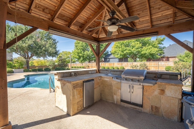 view of patio with an outdoor wet bar, a fenced in pool, area for grilling, exterior kitchen, and ceiling fan