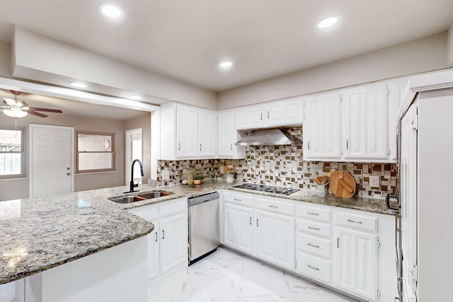 kitchen with white cabinets, wall chimney range hood, sink, kitchen peninsula, and stainless steel dishwasher