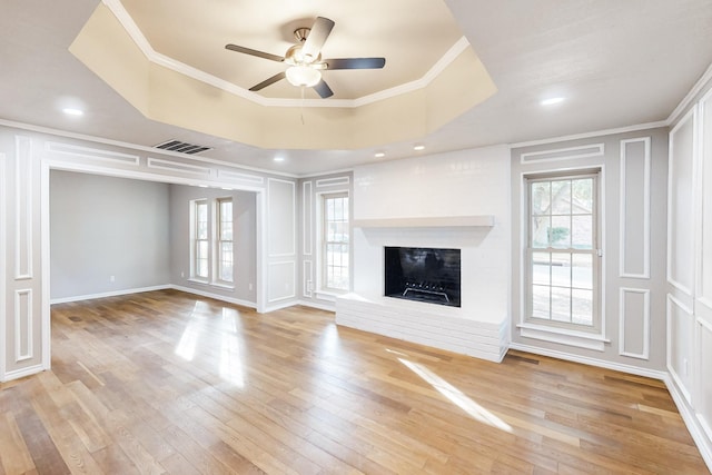 unfurnished living room with hardwood / wood-style flooring, a tray ceiling, and ornamental molding