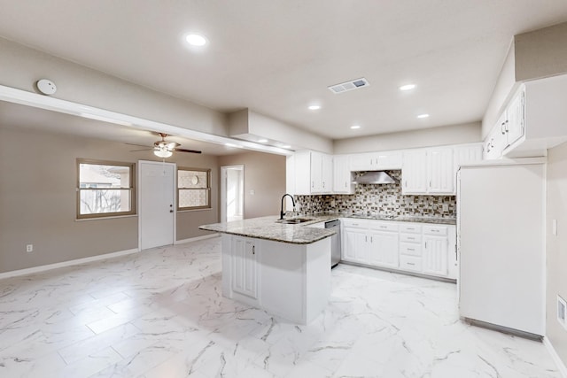 kitchen with white fridge, decorative backsplash, stainless steel dishwasher, white cabinets, and kitchen peninsula