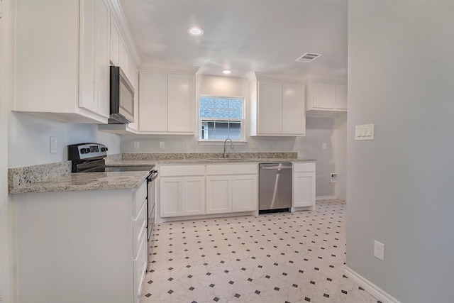 kitchen with stainless steel appliances, white cabinetry, light stone counters, and sink