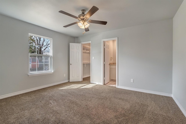 unfurnished bedroom featuring a spacious closet, ceiling fan, ensuite bath, a closet, and light colored carpet