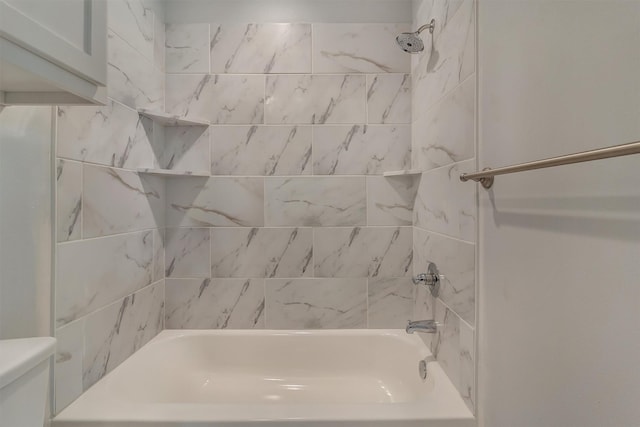 bathroom featuring tiled shower / bath combo and toilet