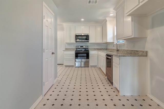 kitchen featuring light stone countertops, appliances with stainless steel finishes, sink, and white cabinetry