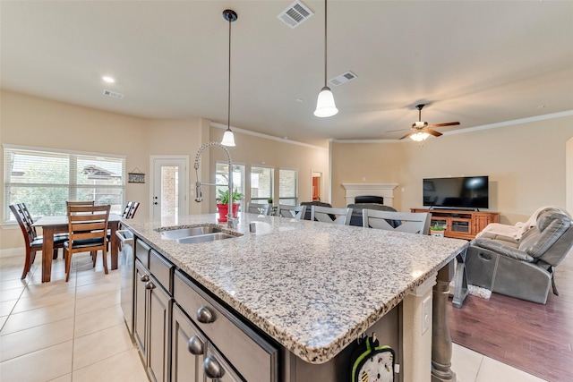 kitchen featuring sink, light tile patterned floors, stainless steel dishwasher, pendant lighting, and a kitchen island with sink