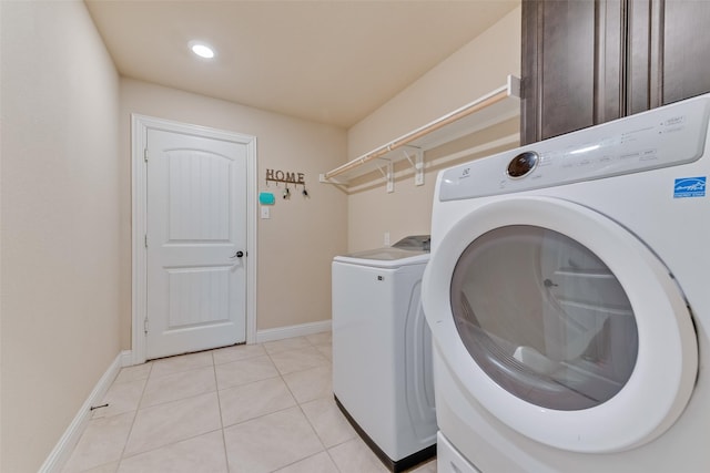 clothes washing area featuring cabinets, light tile patterned flooring, and washer and dryer