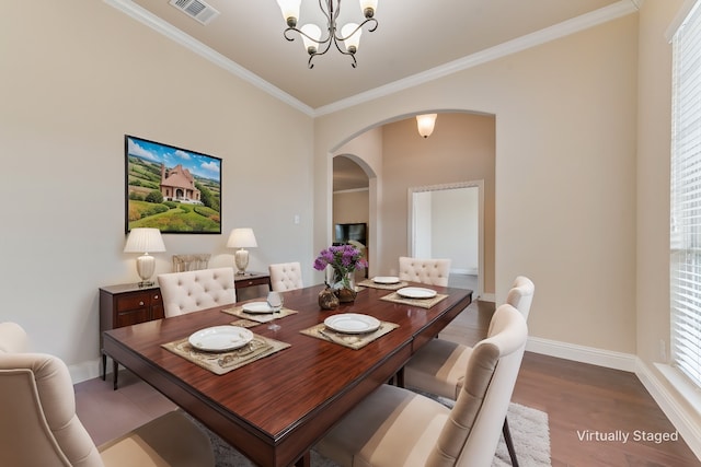 dining space with wood-type flooring, ornamental molding, and a chandelier