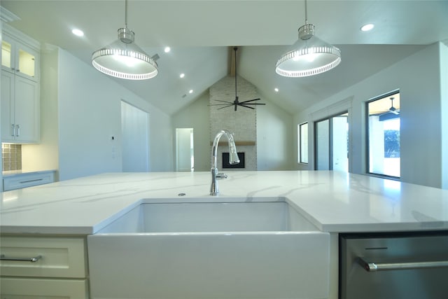 kitchen with white cabinetry, a center island with sink, light stone countertops, pendant lighting, and sink