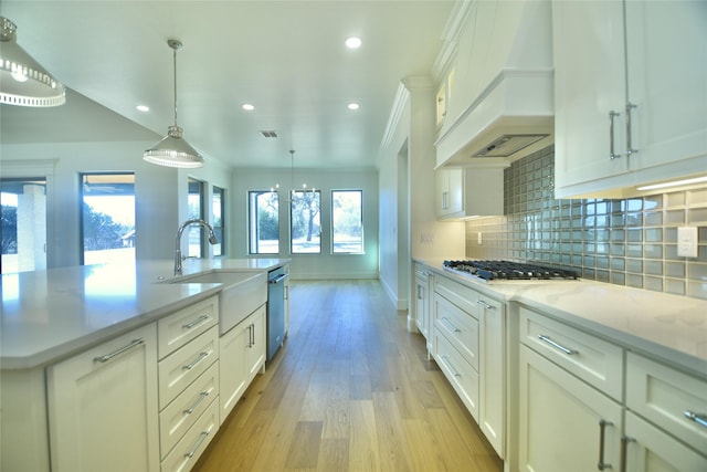 kitchen featuring appliances with stainless steel finishes, decorative backsplash, sink, hanging light fixtures, and custom range hood