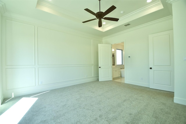 carpeted empty room with ceiling fan, a tray ceiling, and ornamental molding