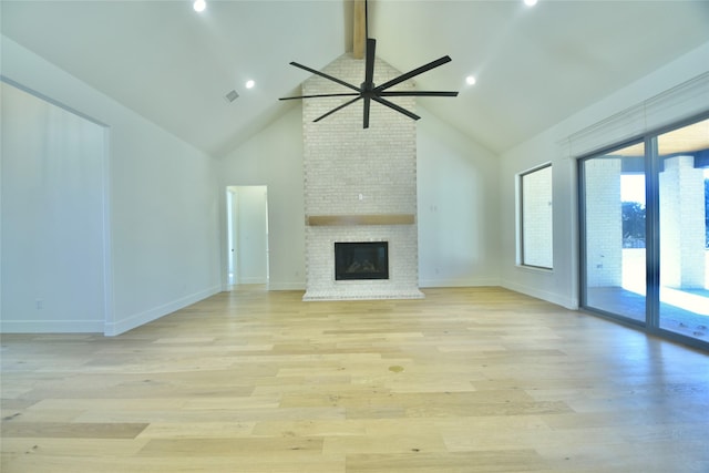 unfurnished living room featuring a brick fireplace, ceiling fan, light hardwood / wood-style flooring, and beamed ceiling