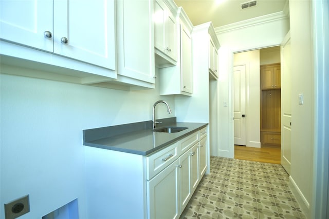 kitchen with sink, white cabinetry, and ornamental molding