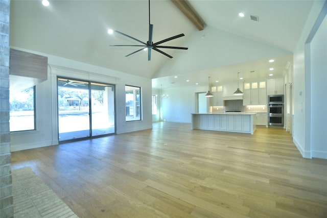 unfurnished living room featuring ceiling fan, vaulted ceiling with beams, and light hardwood / wood-style flooring