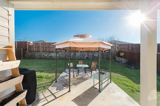 view of yard with a gazebo, a fenced backyard, outdoor dining space, and a patio area