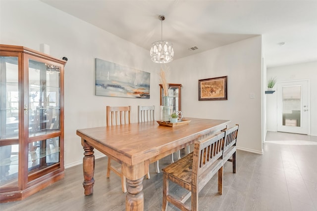 dining area featuring visible vents, baseboards, an inviting chandelier, and wood finished floors