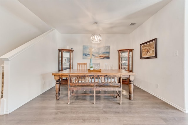 dining area featuring a notable chandelier, wood finished floors, visible vents, and baseboards