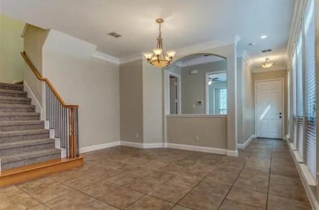 interior space with ornamental molding, tile patterned flooring, and ceiling fan with notable chandelier