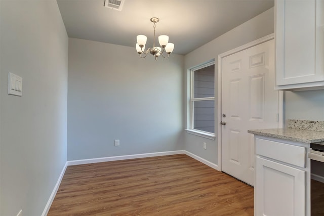 unfurnished dining area featuring light hardwood / wood-style flooring and a chandelier