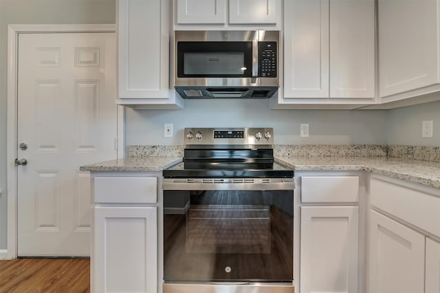 kitchen featuring light stone countertops, white cabinets, appliances with stainless steel finishes, and light hardwood / wood-style floors