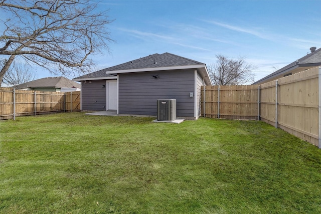 rear view of property with central AC and a yard