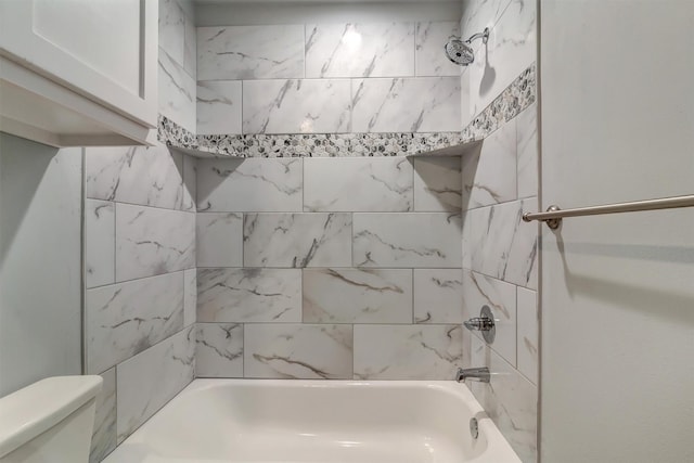 bathroom with tiled shower / bath combo and toilet