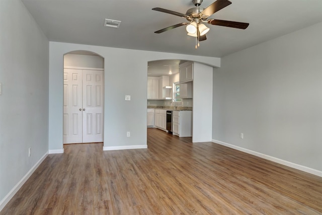 unfurnished living room featuring ceiling fan, sink, and light wood-type flooring