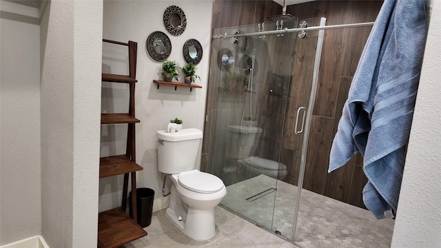 bathroom with tile patterned floors, toilet, and a shower with door