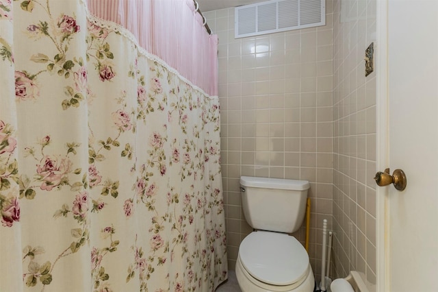 bathroom with toilet and tile walls