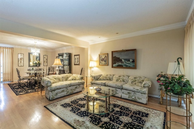 living room featuring wood-type flooring, an inviting chandelier, a textured ceiling, and crown molding