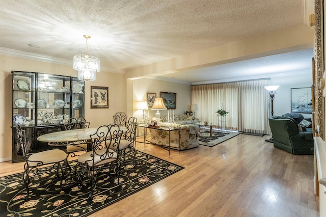 living room featuring hardwood / wood-style flooring, a textured ceiling, crown molding, and a notable chandelier